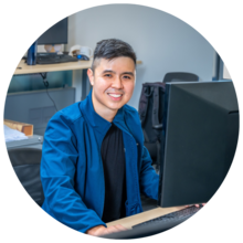 Benedict Chen sits in front of a large computer monitor in an office. Image credit: Javier Flores